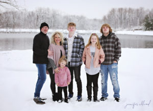 family photo in the snow with pond in the background