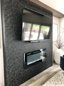 black fireplace wall with wallpaper design and tv
