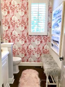 pink and grey wallpaper in powder bath with faux fur bench and rug