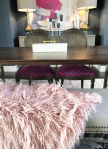 long and skinny table with two chairs and a pink shag throw