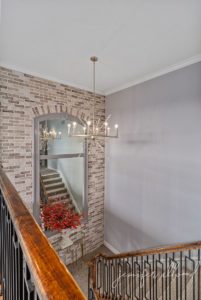final product of light brick wall and big mirror above stairs