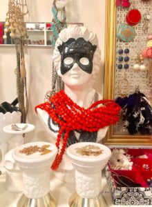 mannequin head holding necklases and milk glass vases holding small necklaces
