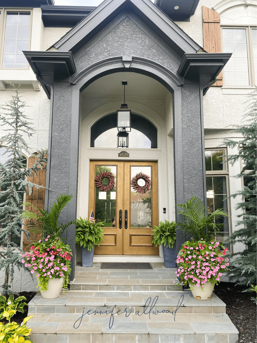flower planters on front patio with pink flowers and greenery 